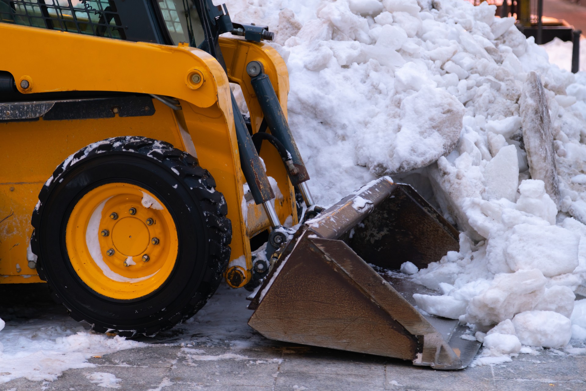 Heavy duty earth mover cleaning snow off the sidewalks after blizzard.